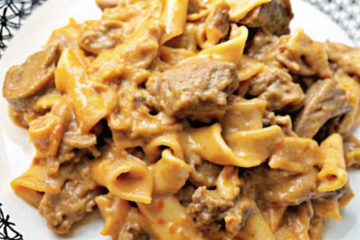Serving Slow Cooker Ground Beef Stroganoff over egg noodles